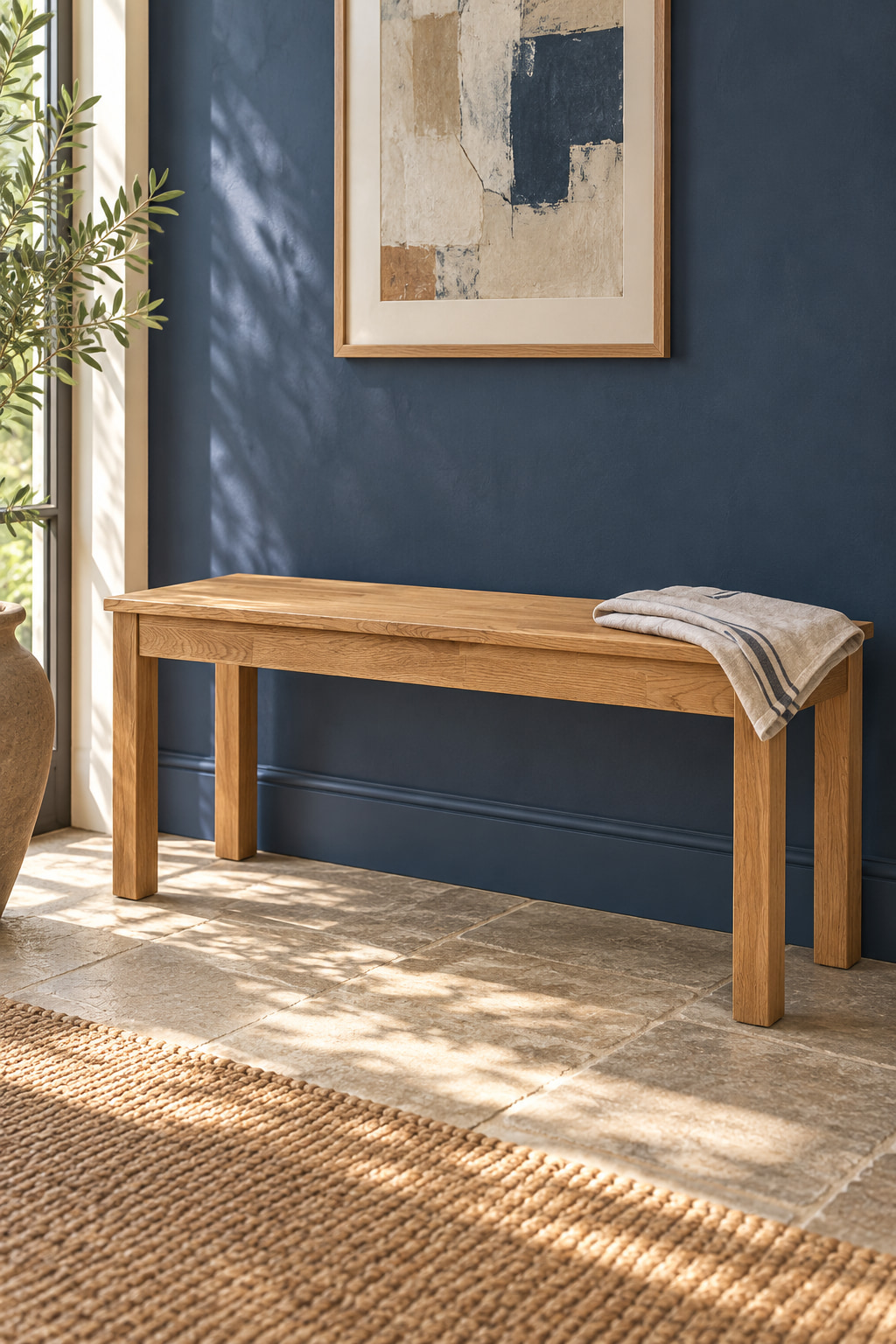 Simple oak bench against an indigo wall beneath a framed picture.