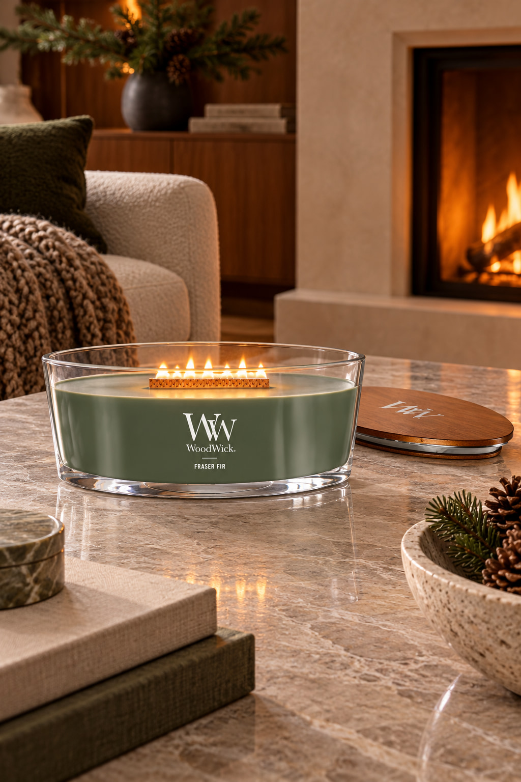 A low oval glass candle filled with green wax and a long wooden wick, its wooden lid beside it on a stone coffee table.