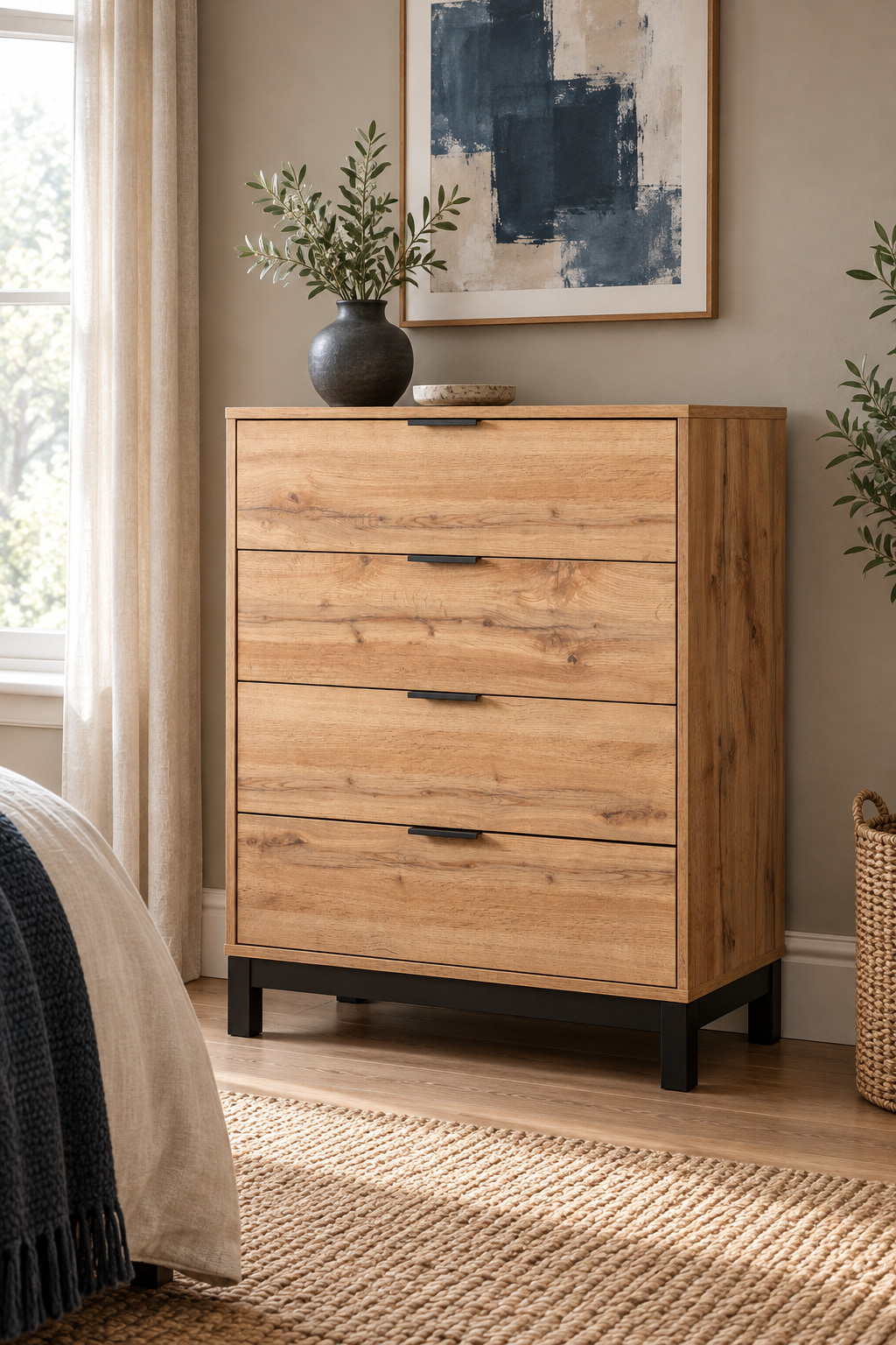Oak-effect four-drawer chest with black handles beneath wall-hung artwork.
