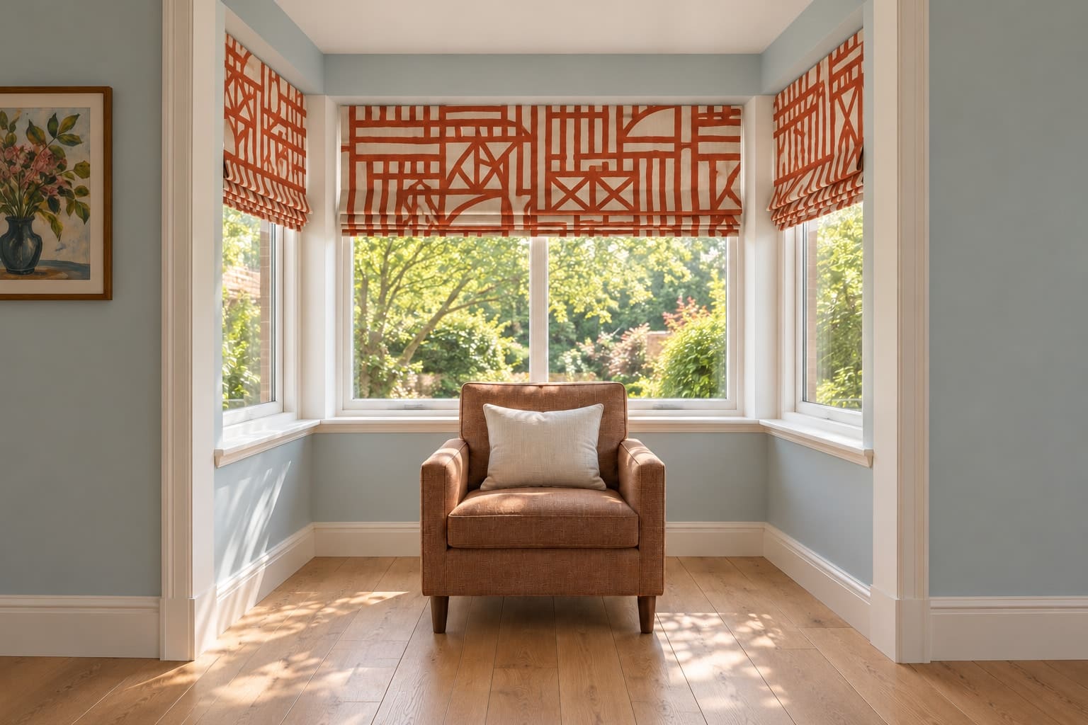 A pale blue rectangular bay with three separate rust-and-ecru Roman blinds, a compact cinnamon armchair and clear oak floor.