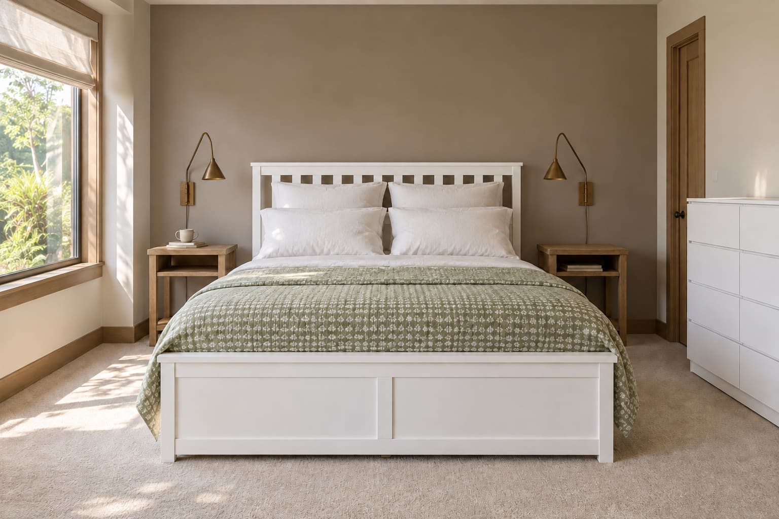 Minimalist bedroom with a white slatted ottoman bed square to a clay-toned wall, sage quilt, timber bedside tables, unlit brass wall lamps and a white eight-drawer chest.