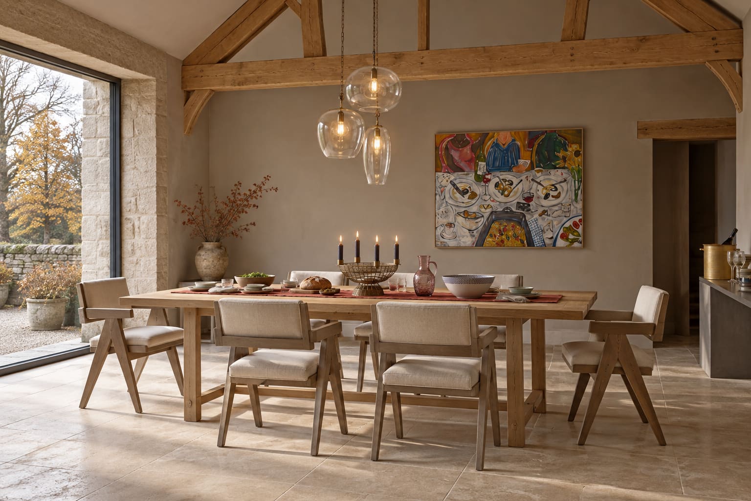 Converted-barn dining room with a long timber table, upholstered chairs, glass pendant lighting and shared serving pieces.