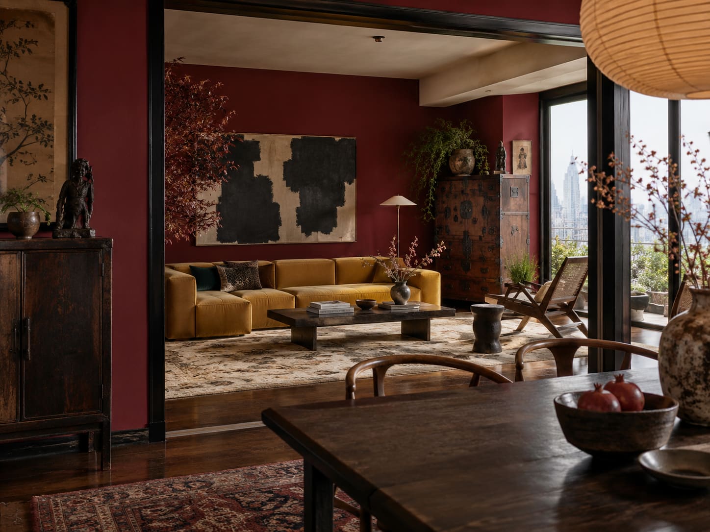 Oxblood living room with an ochre sofa, cane chair and dark cabinet, viewed through an opening from a dining table.