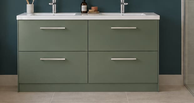 Sage-green double-basin vanity with four equal drawers and slim silver handles against a deep blue-green wall.